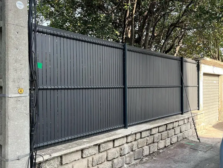 Portail coulissant en aluminium anthracite sur un mur en pierre